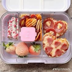 a plastic container filled with different types of food and strawberries on top of it