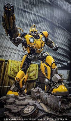 a yellow and black robot standing on top of a rock
