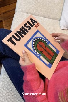 Person holding a photo album labeled Tunisia 2025, showcasing a traditional door design, perfect for travel memories