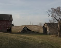 an old barn sits in the middle of a field