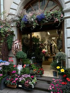 an entrance to a flower shop filled with lots of flowers