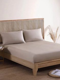 a bed with beige sheets and pillows in a room