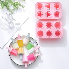 several popsicle molds are on a plate next to a cupcake tray with ice cream