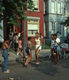 a group of young people standing on the side of a road next to tall buildings