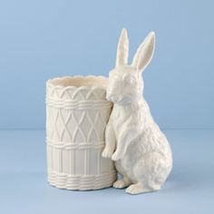 a white ceramic rabbit sitting next to a cup
