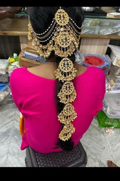 the back of a woman's head with gold jewelry on it