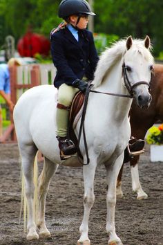 a woman riding on the back of a white horse