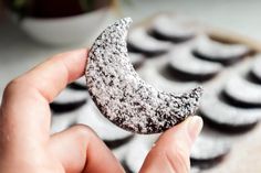 a person holding up a half eaten cookie in front of some cookies on a table
