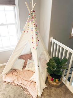a teepee is sitting on the floor next to a potted plant