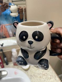 a person holding up a ceramic panda mug
