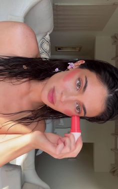 a woman is brushing her hair with an electric blow dryer