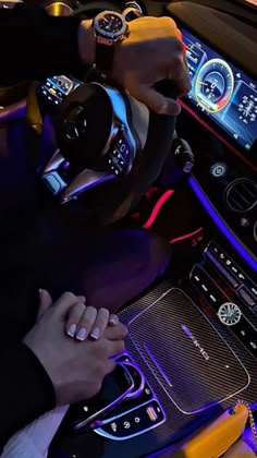 a person is driving a car with the steering wheel and dashboard lights illuminated in blue