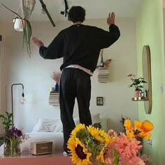 a man standing on top of a bed next to flowers