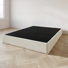 an empty room with a mattress on the floor and wooden parquet floors in front of it