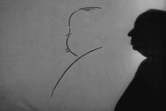 a man standing in front of a white wall with a drawing on it's side