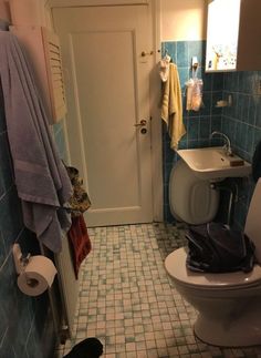 a bathroom with blue tiles and white fixtures, including a toilet in the corner next to a sink