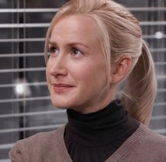 a woman with blonde hair wearing a turtle neck sweater and looking off to the side