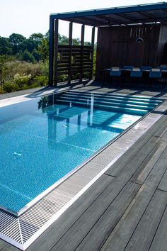 an empty swimming pool with wooden decking and blue tiles on the floor next to it