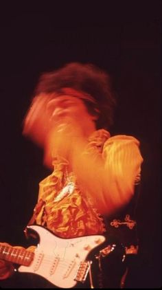 a blurry image of a man playing an electric guitar