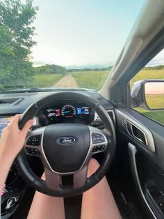 a woman driving a car down a country road