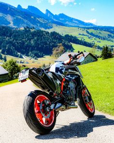 a black motorcycle parked on the side of a road near grass and mountains in the background