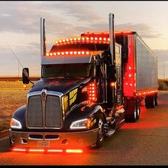a semi truck with its lights on driving down the road