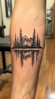 a man's leg with a black and white tattoo of trees on the water