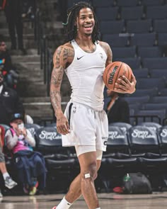 a man with dreadlocks holding a basketball in front of an arena full of people