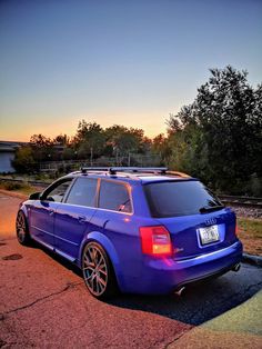 the blue car is parked on the side of the road with its roof rack up