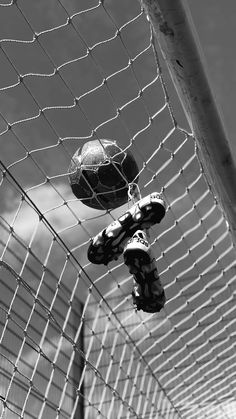 two soccer balls sitting on top of a net next to each other in black and white