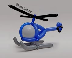 a blue and white toy helicopter is flying in the air with its legs spread out