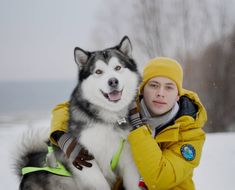 a woman in yellow jacket sitting next to husky dog