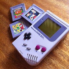 an old nintendo gameboy sitting on top of a wooden table next to video games