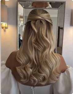 the back of a woman's head with long blonde hair in front of a mirror