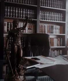 a desk with a statue on it in front of a bookcase filled with books