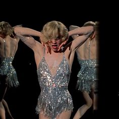 the woman is wearing silver sequins on her body and holding her hands behind her head