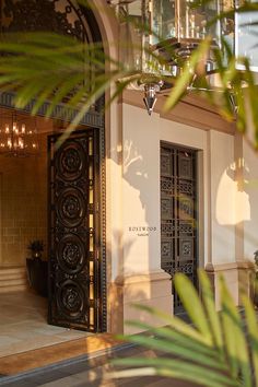 an entrance to a building with plants in the foreground and chandeliers above it