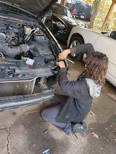 a man working on the hood of a car with his hands in front of it