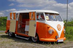 an orange and white vw bus is parked in the grass