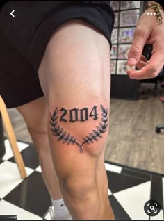 a person with a tattoo on their leg that reads, 2013 and is holding a cell phone