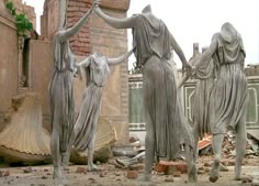 three statues standing next to each other in front of a brick wall and rubbleed building