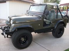 a green jeep parked in front of a house