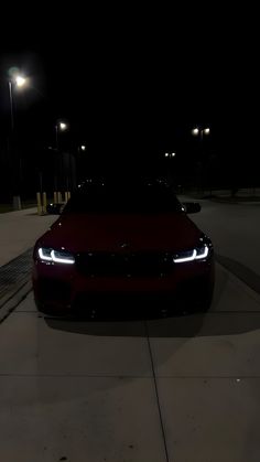 a red car parked on the side of a road at night