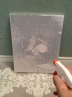 a hand holding an orange and white object in front of a photo on a wall