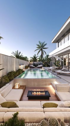 an outdoor living area with couches and a fire pit in front of the pool
