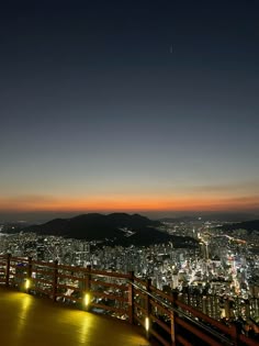 the city lights shine brightly in the night sky from top of a building with wooden railings