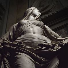 a statue is shown in black and white, with an intricately draped cloth covering it's body