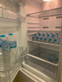 an open refrigerator filled with water and bottled drinks