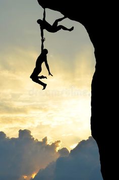 a man hanging from the side of a cliff while holding onto another person on a rope