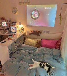 a cat laying on top of a bed in front of a projector screen above it